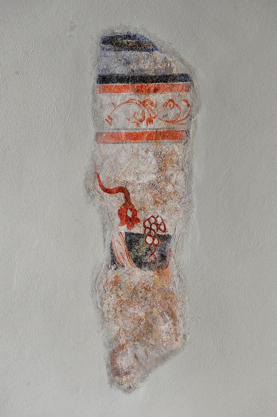 Fragment odrestaurowanej polichromii na ścianie, z widocznymi warstwami farby i detalami dekoracyjnymi, w tym motywem roślinnym i geometrycznym, po konserwacji.