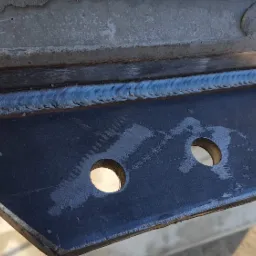 Spoina spawalnicza łącząca stalowy element z betonową konstrukcją, widoczne dwa otwory w metalowym elemencie.