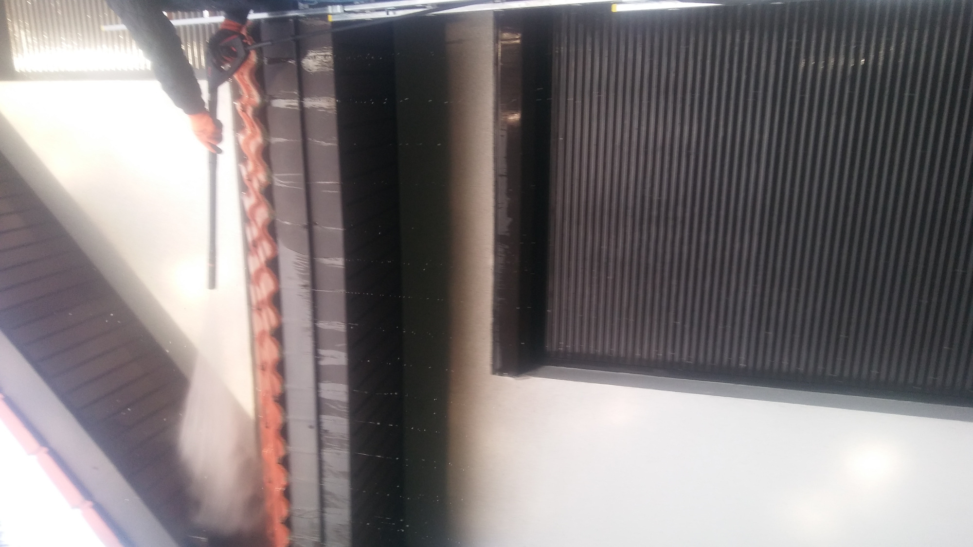 Czyszczenie elewacji budynku myjką ciśnieniową, widoczne ślady spływającej wody i czyszczona powierzchnia.