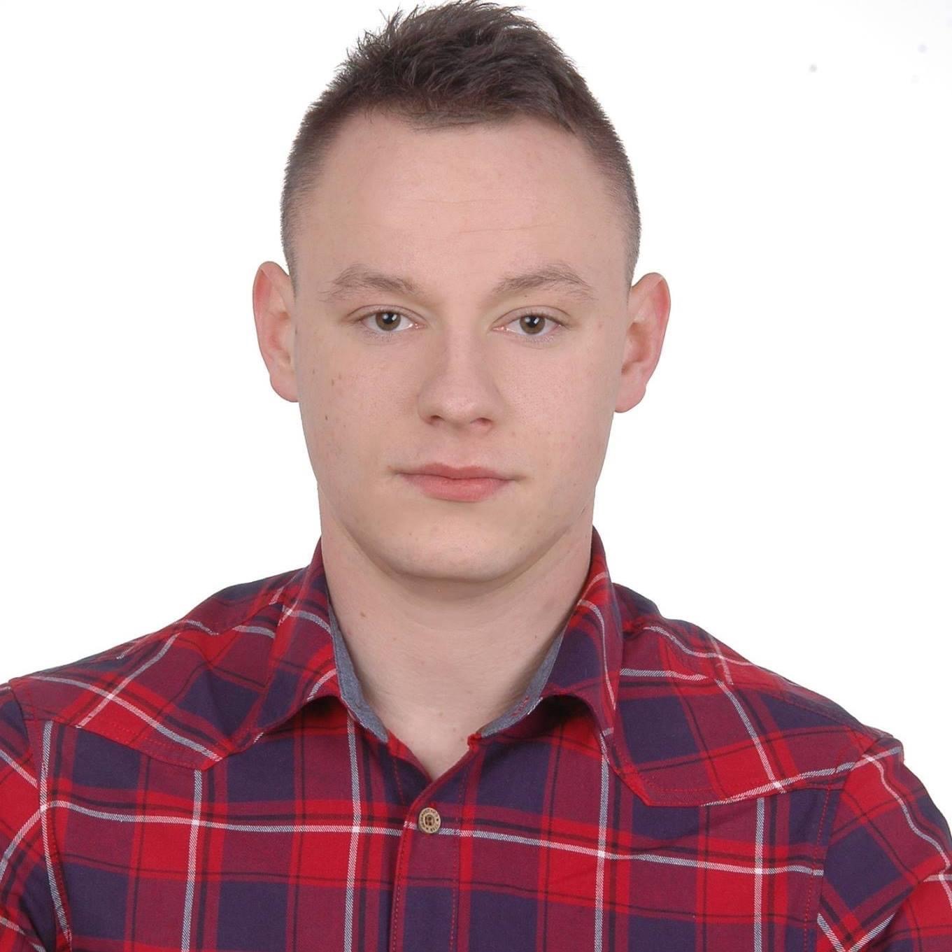 Młody mężczyzna w czerwono-granatowej koszuli w kratę na białym tle, portret.