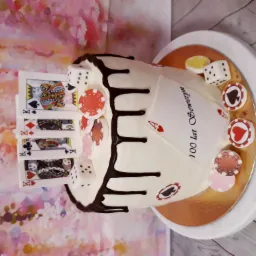 Tort urodzinowy w stylu kasyna z kartami Królów, kostkami, żetonami i polewą czekoladową na tle abstrakcyjnym.