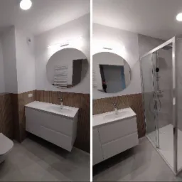 Nowoczesna łazienka po metamorfozie: kabina prysznicowa, okrągłe lustro i umywalka z szafką. Drewnopodobne panele ścienne dodają ciepła szarej tonacji.