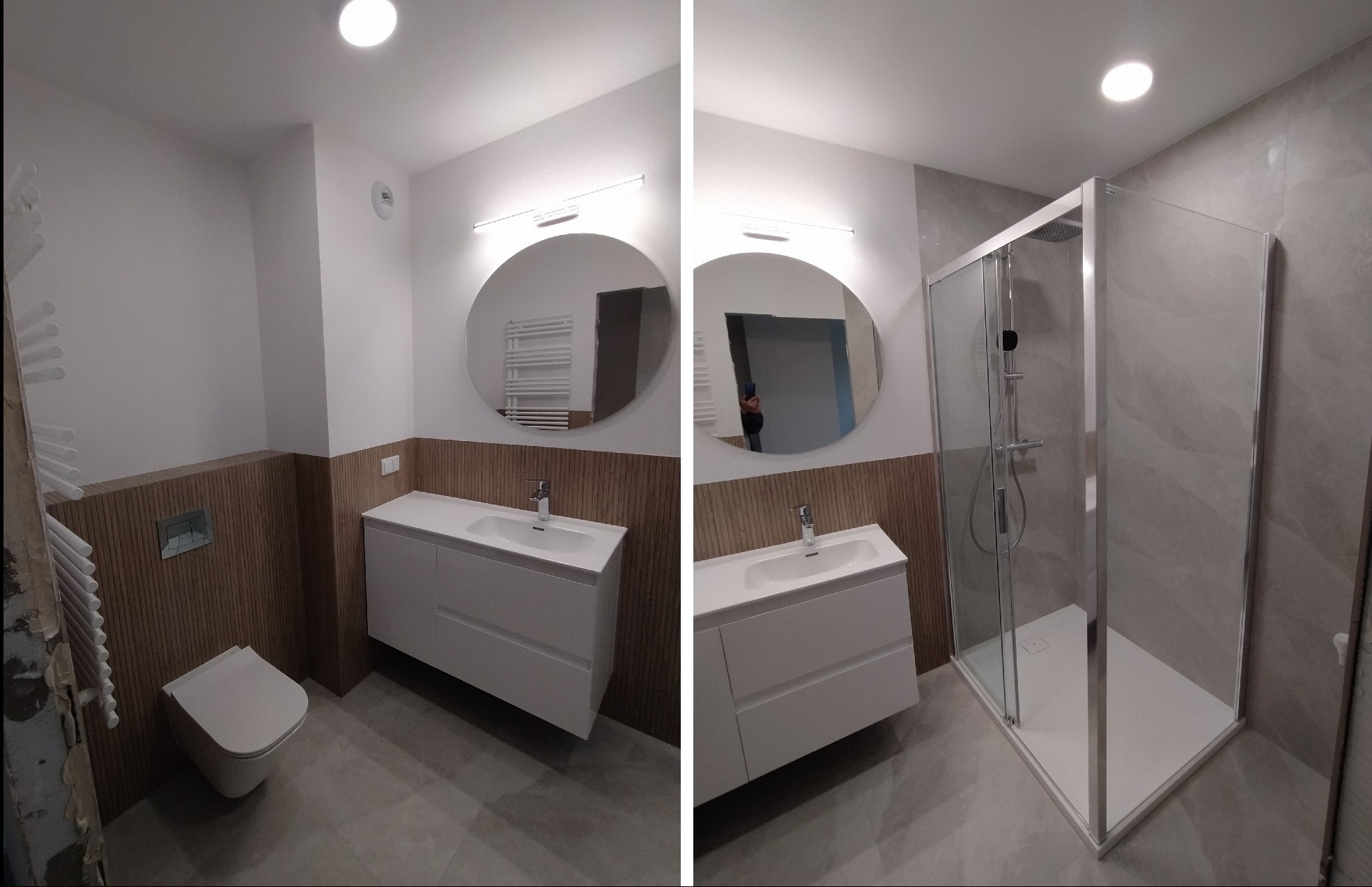 Nowoczesna łazienka po metamorfozie: kabina prysznicowa, okrągłe lustro i umywalka z szafką. Drewnopodobne panele ścienne dodają ciepła szarej tonacji.
