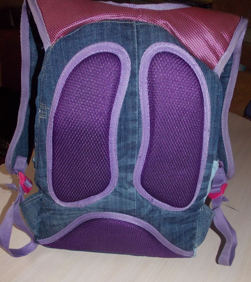Plecak wykonany z przetworzonego denimu z fioletowymi elementami siatkowymi i paskami, widok z tyłu ukazujący detale konstrukcyjne i fakturę materiałów.
