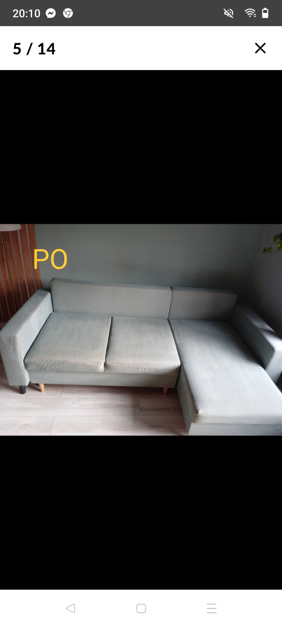 Jasnoszara kanapa narożna z trzema siedziskami i krótkim szezlongiem po prawej stronie, stojąca na drewnianej podłodze w pokoju z szarą ścianą, z widocznym napisem 'PO' na zdjęciu.