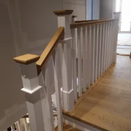 Białe balustrady z drewnianymi poręczami na schodach, widok z góry na dół.