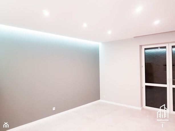 Wnętrze pokoju po remoncie: szara ściana z podświetleniem LED przy suficie, biała podłoga i białe drzwi balkonowe.