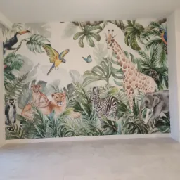 Pokój z fototapetą przedstawiającą zwierzęta z dżungli: lwy, żyrafę, zebrę, słonia, tukana i papugi, na tle tropikalnej roślinności, z szarymi płytkami na podłodze.