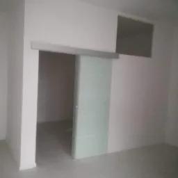 Szklane drzwi przesuwne z poziomymi paskami w nowo wykończonym, pomalowanym na biało pomieszczeniu z widoczną wnęką w ścianie.