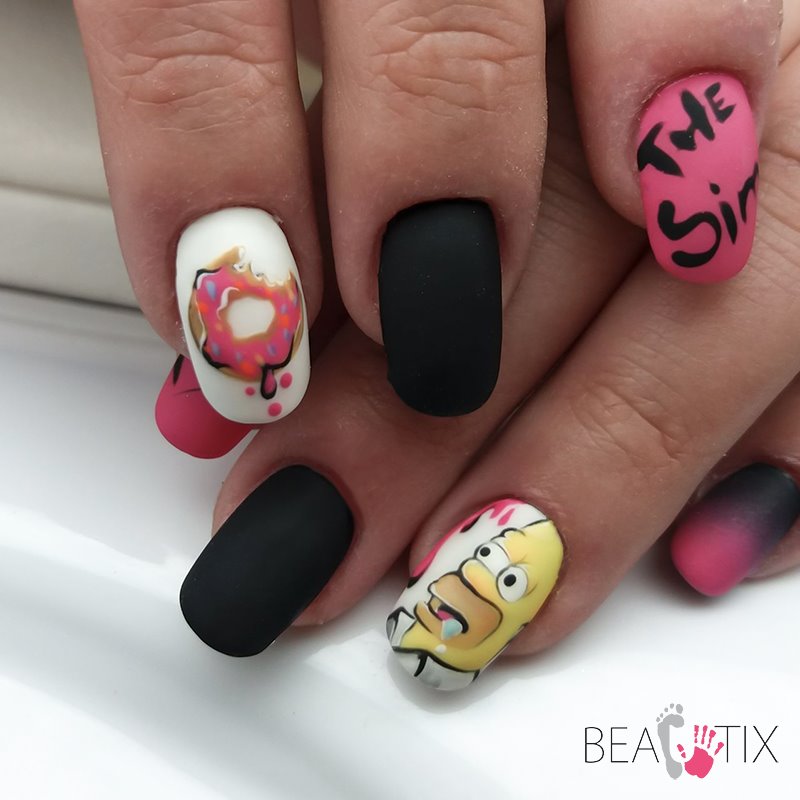 Zbliżenie na dłoń z pomalowanymi paznokciami: jeden z motywem ugryzionego pączka, drugi z Homerem Simpsonem, trzeci z napisem 'The Sim', pozostałe w kolorze czarnym matowym i różowym ombre.