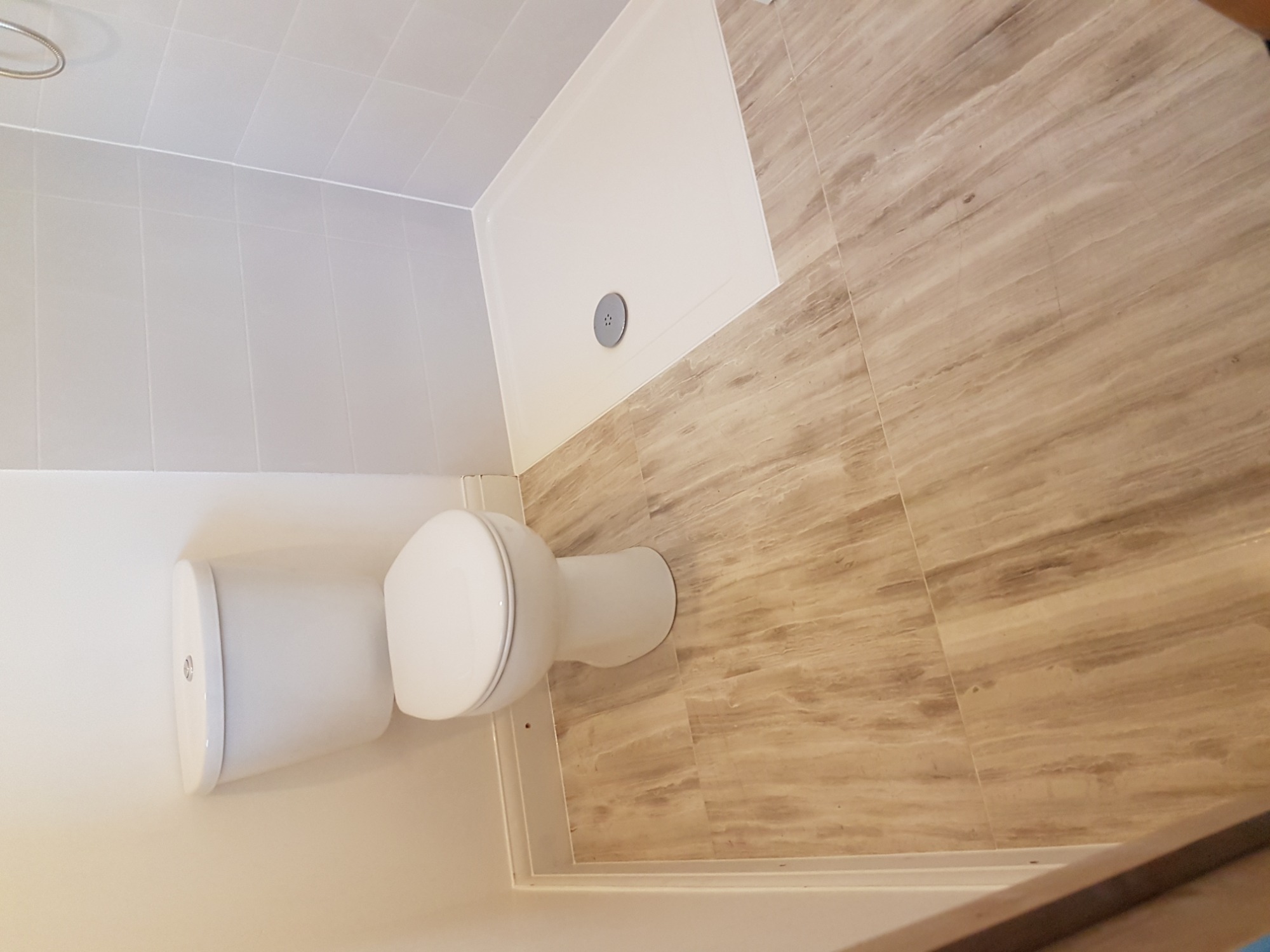 Wykończona łazienka z kabiną prysznicową i toaletą, wyłożona płytkami imitującymi drewno, widok z góry.