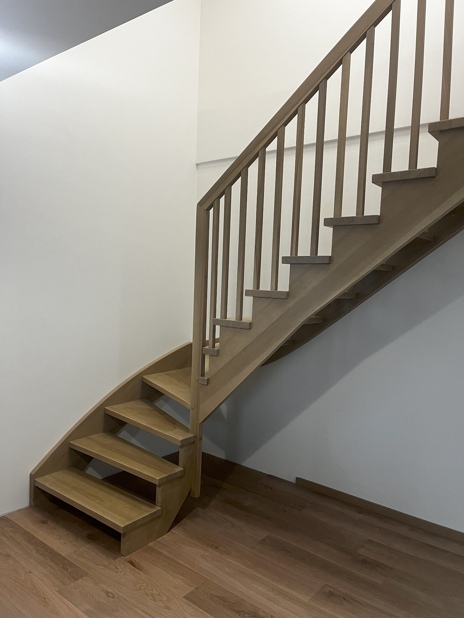 Jasne, drewniane schody z poręczą w nowoczesnym wnętrzu. Widoczne detale wykończenia i naturalna kolorystyka drewna. Minimalistyczny design i precyzyjne wykonanie.