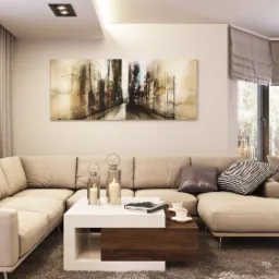 Jasny salon z narożną sofą, stolikiem kawowym z białym blatem i drewnianą wstawką, obrazem abstrakcyjnym na ścianie oraz jadalnią w tle, oświetlony świecami w lampionach.