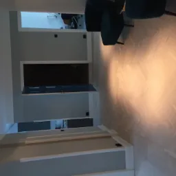 Jasny parkiet ułożony we wzór jodełki francuskiej w korytarzu z otwartymi drzwiami do innych pomieszczeń, widoczne detale wykończenia ścian i oświetlenie punktowe.