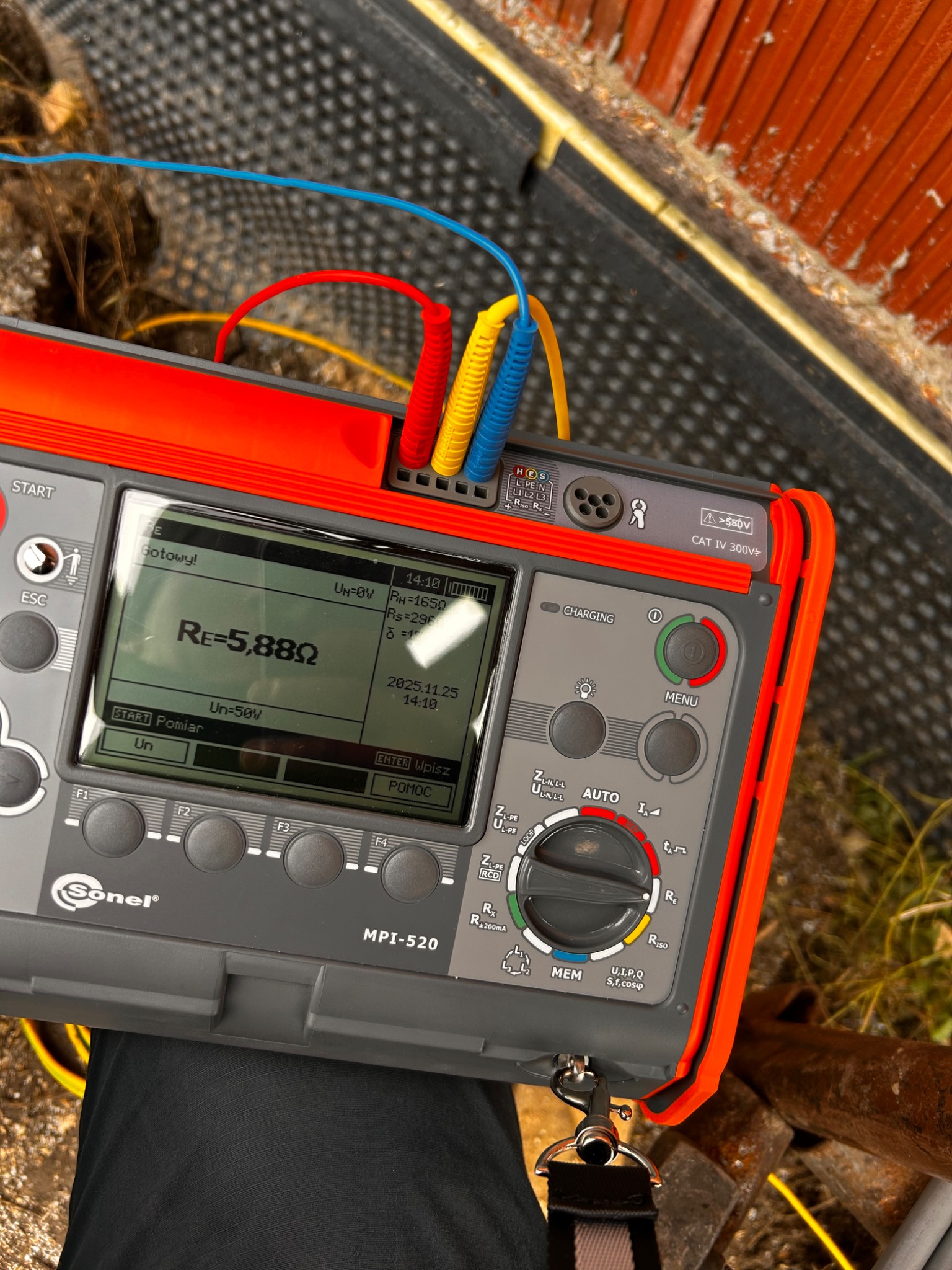 Miernik Sonel MPI-520 z podłączonymi przewodami pomiarowymi, wyświetlający wynik pomiaru rezystancji uziemienia Re=5,88Ω. Widoczny fragment instalacji i narzędzia.