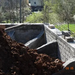 Wykop fundamentów z betonowymi ścianami i zbrojeniami, widoczna sterta ziemi i data 06 05 2016.