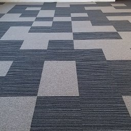 FLOOR-POL - Geometryczny wzór podłogi z płytek dywanowych w odcieniach szarości i granatu, zrealizowany w Starogardzie Gdańskim.