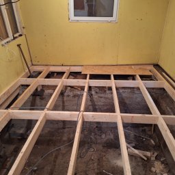 FLOOR-POL - Konstrukcja drewniana pod podłogę w remontowanym pomieszczeniu z żółtymi ścianami, widoczna łopata i fragment płyty OSB.