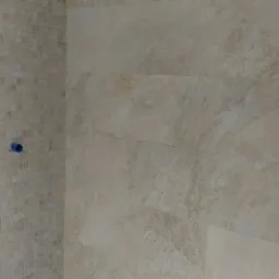 Ściana łazienki wyłożona beżowymi płytkami mozaikowymi i wielkoformatowymi, widoczne przygotowane otwory na instalacje.