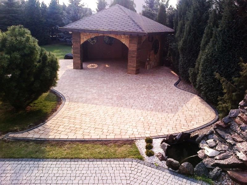 Beżowa kostka na podjeździe z altaną z kamienia i oczkiem wodnym z kaskadą, eleganckie wykończenie ogrodu.