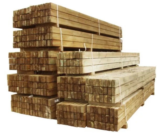 Stosy impregnowanej tarcicy budowlanej na paletach, powiązane sznurkiem, widoczne przekroje belek o kwadratowym kształcie.