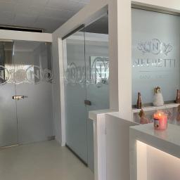 Zakład Szklarski M.S. Sobczyk - Szklane drzwi i ścianki działowe z dekoracyjnym motywem firmy Neffretti w Szczecinie, widoczne z perspektywy recepcji z zapaloną świecą i ozdobami.