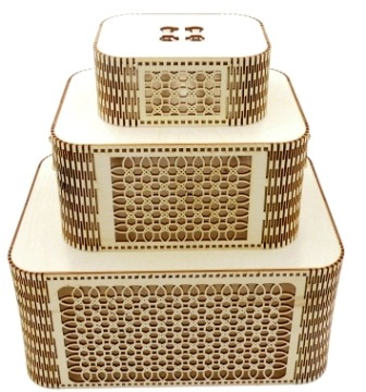 Trzy drewniane, ażurowe pudełka o kwadratowej podstawie, ułożone jedno na drugim w piramidę, od największego na dole do najmniejszego na górze. Każde pudełko ma inny wzór ażurowy.