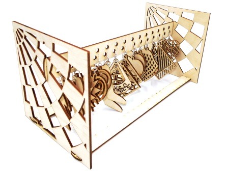 Drewniany, ażurowy organizer na kolczyki w kształcie geometrycznej konstrukcji z wyciętymi wzorami, eksponujący wiszące kolczyki o różnych kształtach.