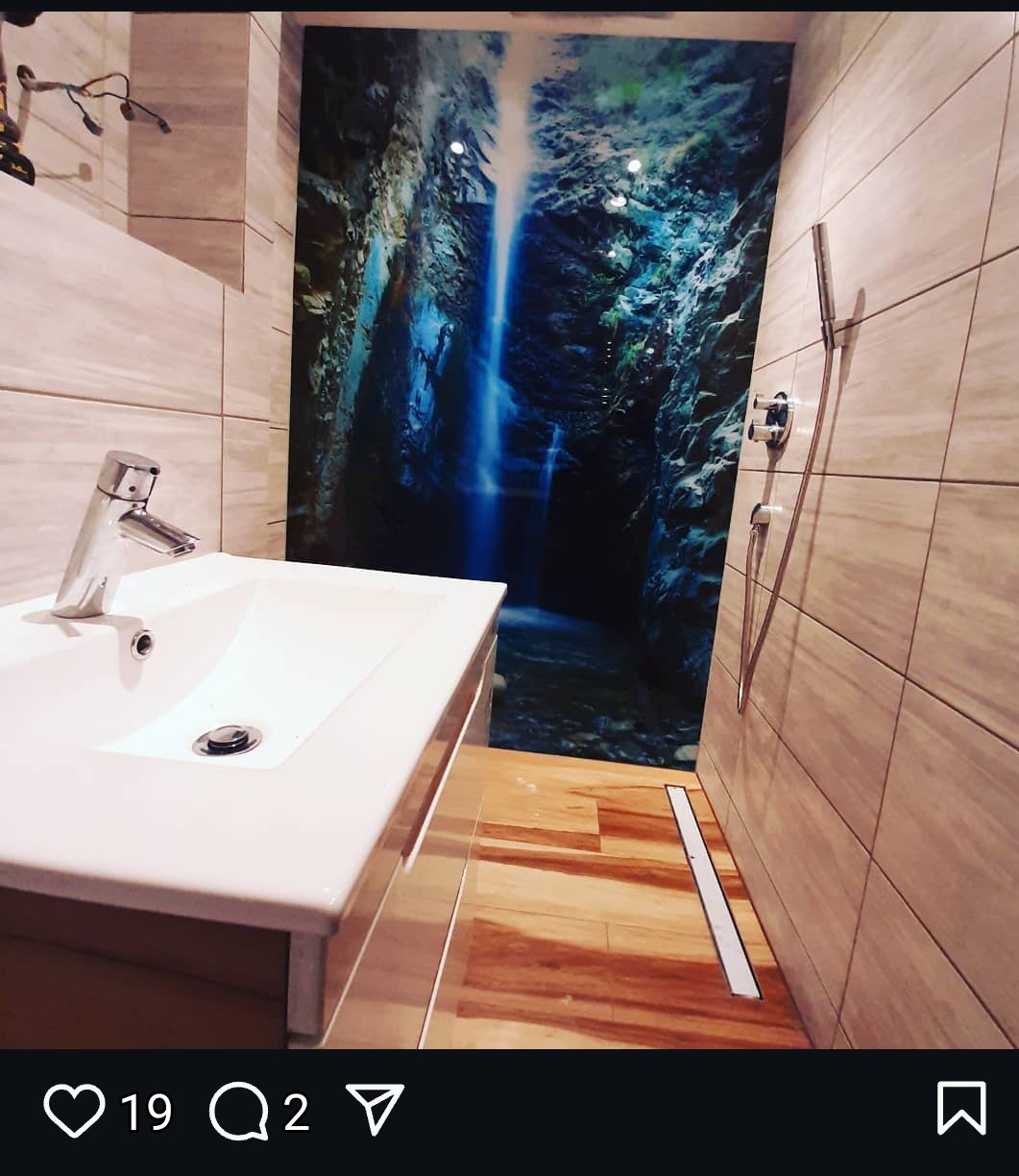 Nowoczesna łazienka z umywalką nablatową, kabiną prysznicową bez brodzika i fototapetą z motywem wodospadu na ścianie.