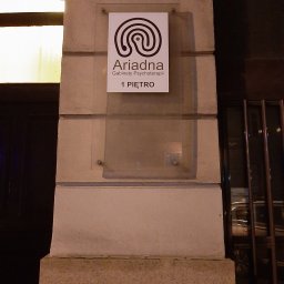 Gabinety Psychoterapii ARIADNA Katowice Opolska - Szyld gabinetu psychoterapii Ariadna na pierwszym piętrze, z logo w formie labiryntu, umieszczony na kamiennej kolumnie budynku.