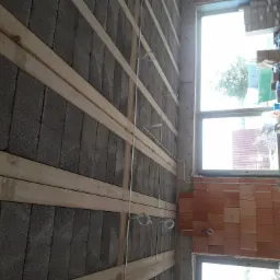 Wewnętrzna ściana z szarego betonu komórkowego z drewnianymi łatami i przewodami elektrycznymi, przygotowana pod instalacje, widok z dołu