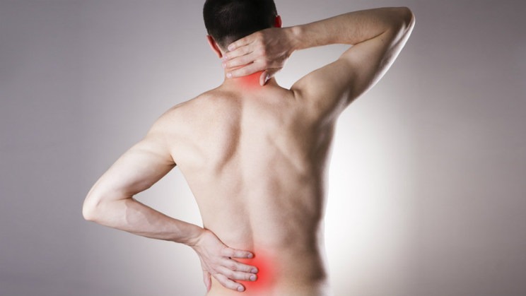 Mężczyzna bez koszulki z widocznymi czerwonymi obszarami na szyi i dolnej części pleców, wskazującymi na ból lub napięcie mięśniowe.