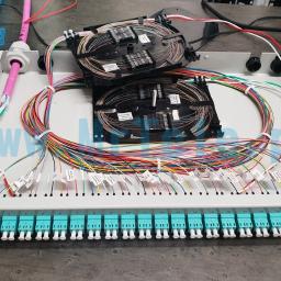 Mr Tele Krzysztof Nowak - Panel światłowodowy z kolorowymi kablami uporządkowanymi wewnątrz obudowy, zakończonymi złączami oznaczonymi etykietami, z dwoma organizerami kabli na górze.