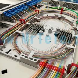 Mr Tele Krzysztof Nowak - Otwarta skrzynka światłowodowa z uporządkowanymi, kolorowymi kablami, złączami i elementami montażowymi, widoczne uchwyty kablowe.