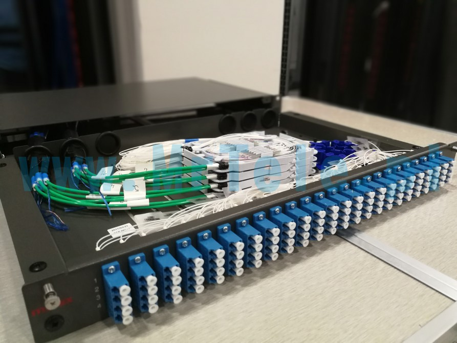 Panel krosowniczy światłowodowy z zielonymi i białymi kablami, widoczne złącza i oznaczenia numeracyjne.