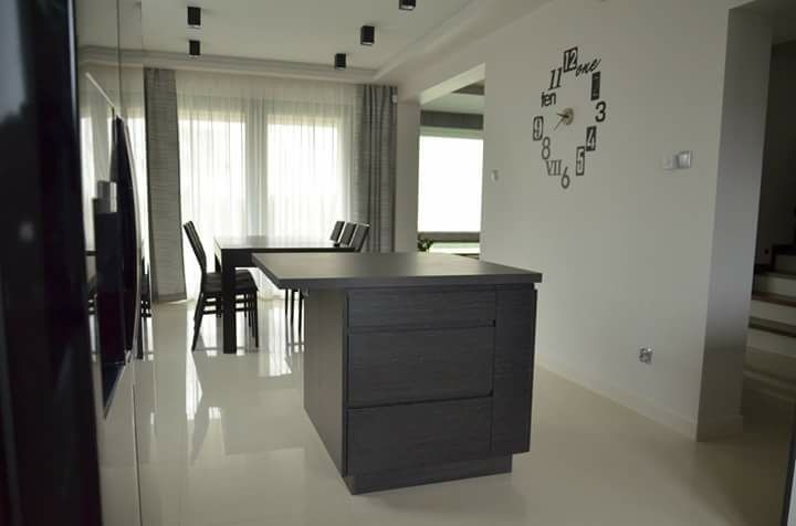 Nowoczesne zasłony w kolorze szarości, delikatnie filtrujące światło dzienne w przestronnym wnętrzu z minimalistycznym zegarem na ścianie.