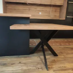 Nowoczesna kuchnia z blatem drewnianym na czarnych, metalowych nogach w kształcie litery X, widok z dołu, ciepłe oświetlenie, drewniana podłoga.