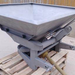 Sandblast - Metalowy rozsiewacz nawozów po renowacji, stojący na palecie, z widocznym mechanizmem regulacji i wałem odbioru mocy.