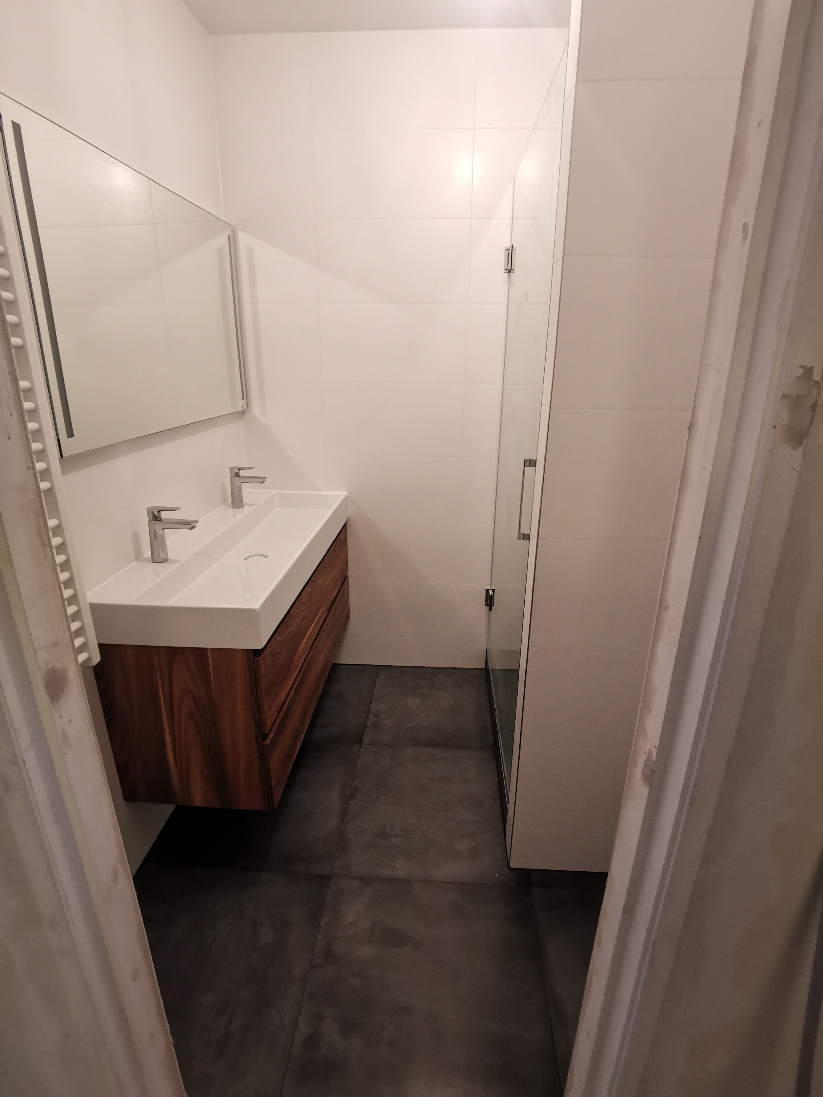 Nowoczesna łazienka z podwójną umywalką nablatową, szafką z forniru drewna egzotycznego i kabiną prysznicową ze szklanymi drzwiami.