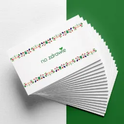 Stos wizytówek z motywem warzyw i owoców, na białym tle z zielonym akcentem, napis 'na zdrowie' z zielonym listkiem.