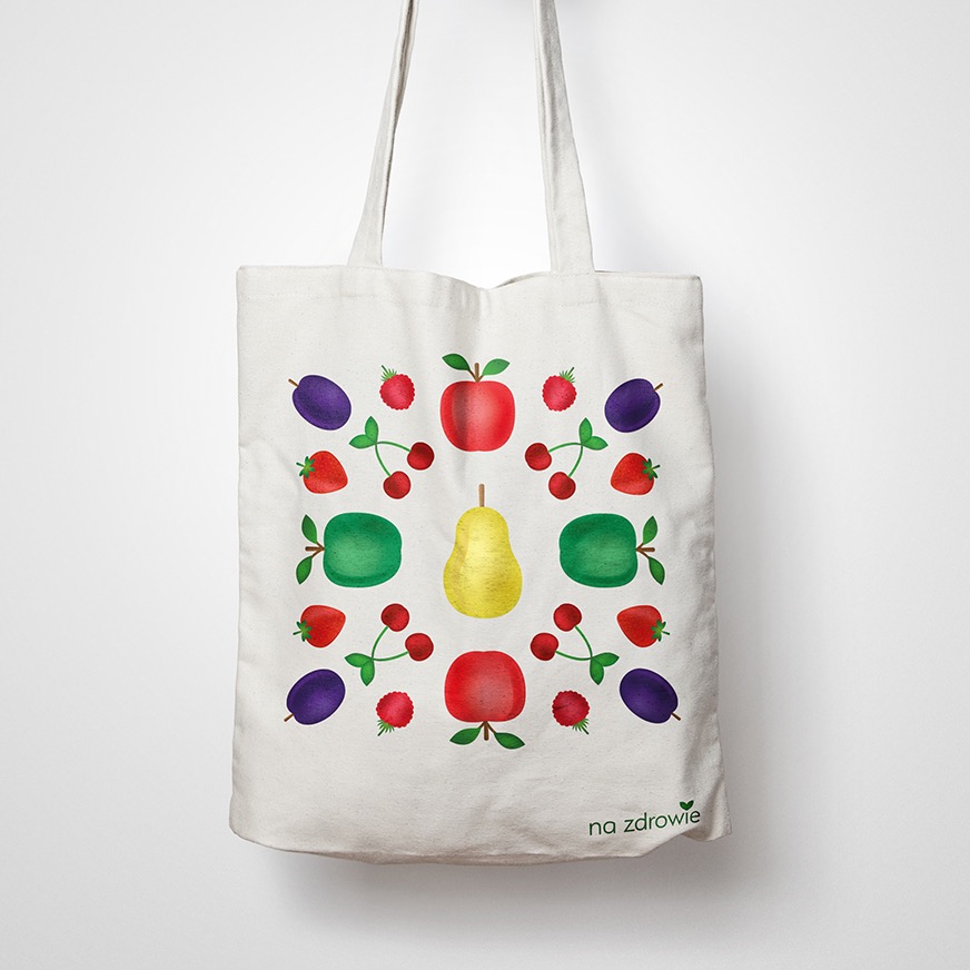 Ekologiczna torba bawełniana z nadrukiem owoców (jabłka, gruszki, śliwki, maliny, wiśnie, truskawki) i napisem 'na zdrowie', wisząca na białym tle.