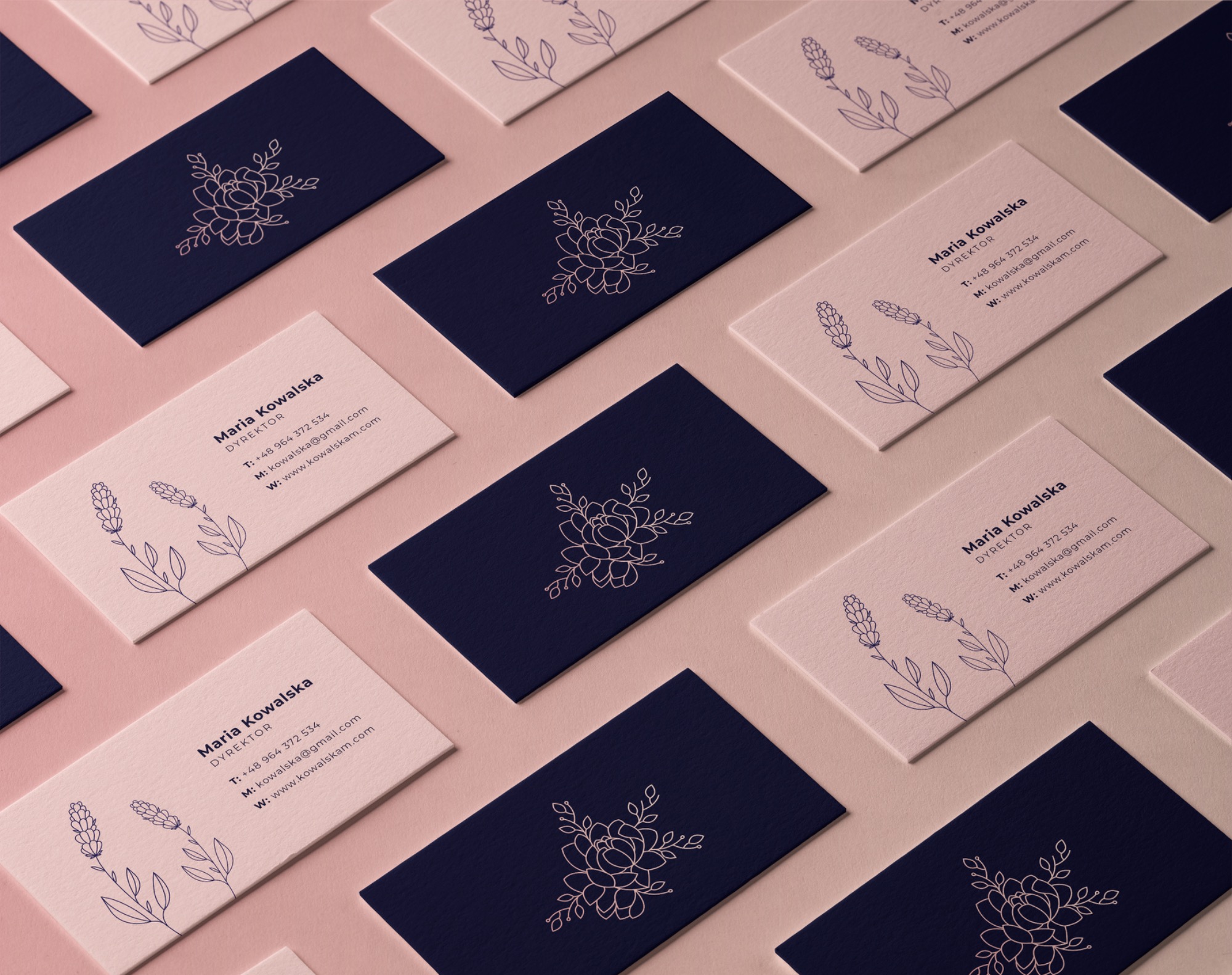 Różowe i granatowe wizytówki z minimalistycznym motywem kwiatowym, ułożone pod kątem na gładkim, beżowym tle. Detalistyka i precyzja wykonania.
