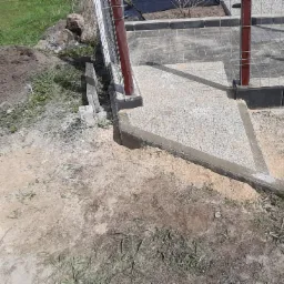 Budowa ogrodowego chodnika z kostki brukowej; widoczne betonowe obrzeża, częściowo ułożona kostka i przygotowane podłoże z piasku.