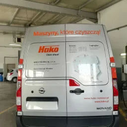 Oklejony srebrny samochód dostawczy marki Opel Movano z grafiką firmy Hako, prezentujący hasło 'Maszyny, które czyszczą!', wraz z danymi kontaktowymi i mapą Polski z zaznaczonymi siedzibami firmy.