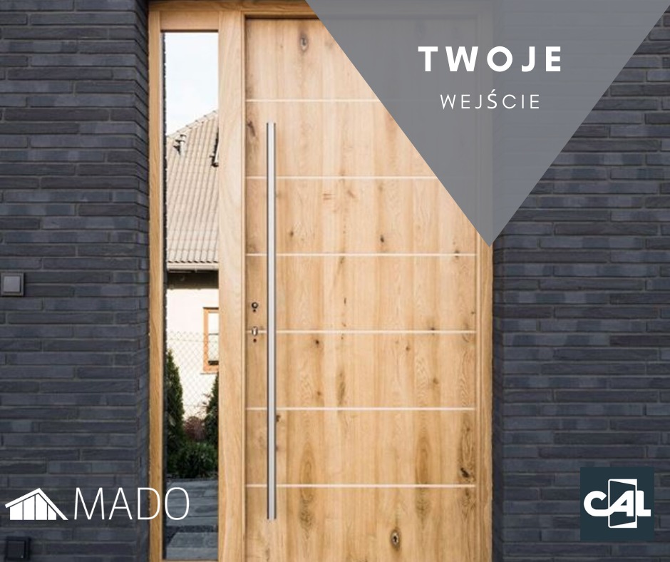 Drewniane drzwi wejściowe z długim, pionowym uchwytem, umieszczone w murze z ciemnej cegły, widoczne logo firmy MADO i CAL.
