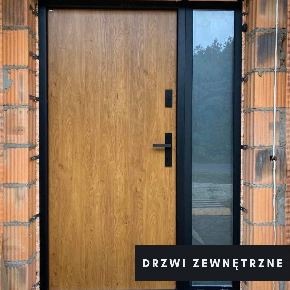 Nowe drzwi wejściowe z drewnopodobnym panelem i czarną ramą, zamontowane w surowym murze z cegieł, z bocznym przeszkleniem.