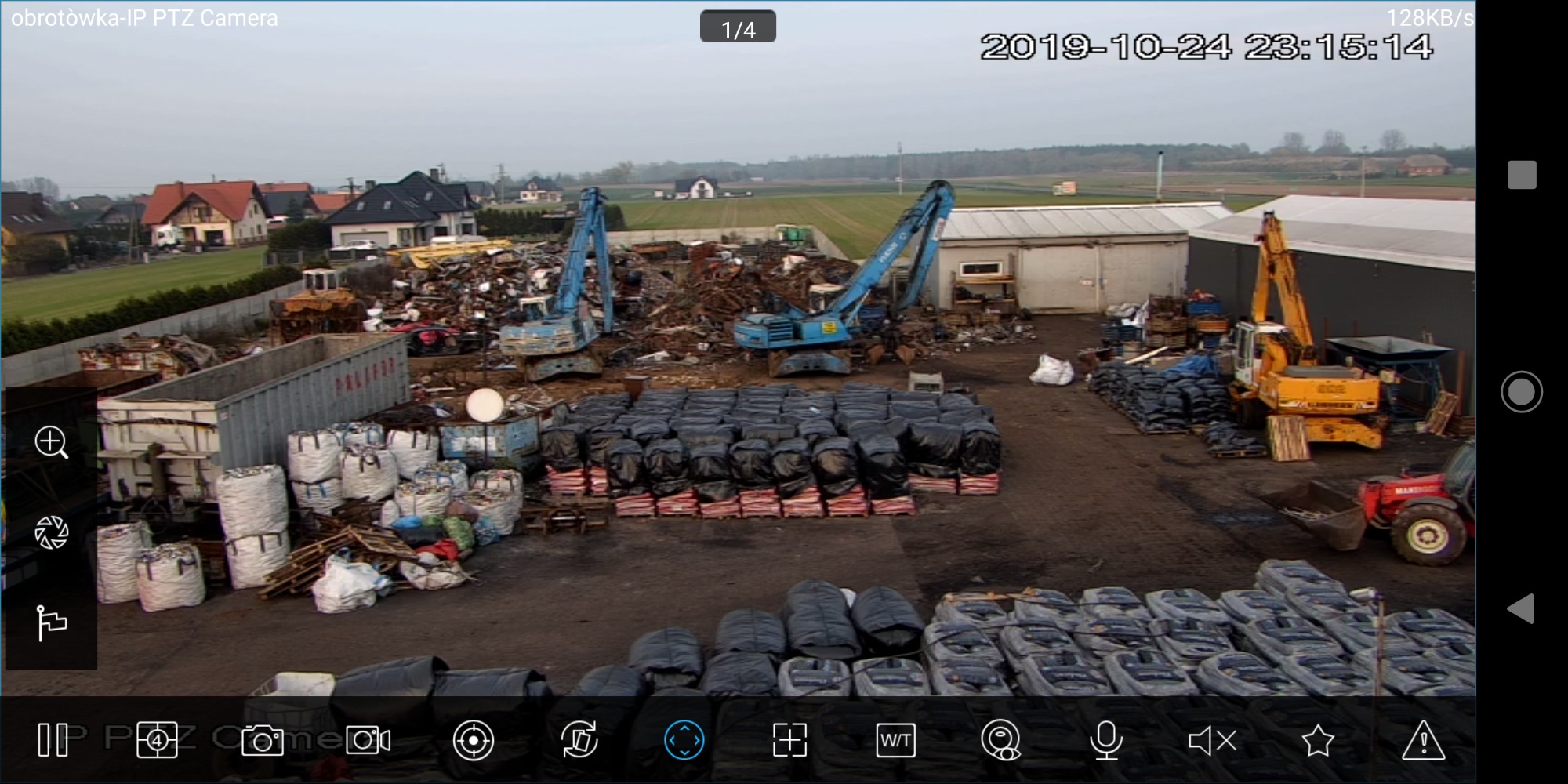 Szeroki kadr z kamery przemysłowej przedstawiający plac składowy z rzędami worków z opałem, koparkami i innymi maszynami budowlanymi w tle, nagranie z 24 października 2019.