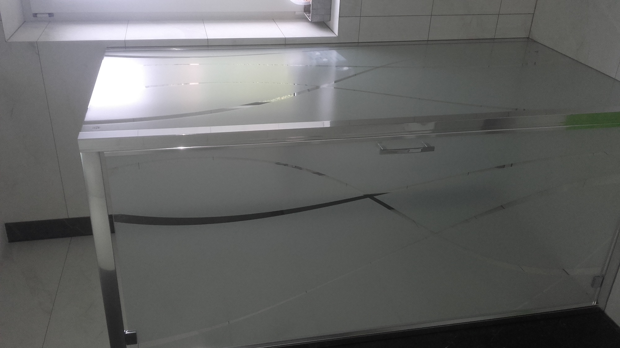 Szklana kabina prysznicowa z matowym wzorem geometrycznym w nowoczesnej łazience z białymi płytkami.