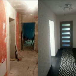 Korytarz w trakcie remontu: po lewej stronie ściany z resztkami starej farby i gipsu, po prawej - ściana wykończona tapetą imitującą białą cegłę, ciemna podłoga i dywanik w geometryczne wzory...