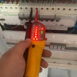 Sprawdzanie napięcia w rozdzielnicy elektrycznej za pomocą testera Fluke T100, widoczne wskaźniki napięcia L1 i L2 oraz diody sygnalizujące poziom napięcia